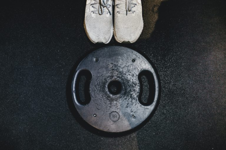 black weight plate beside white sneakers